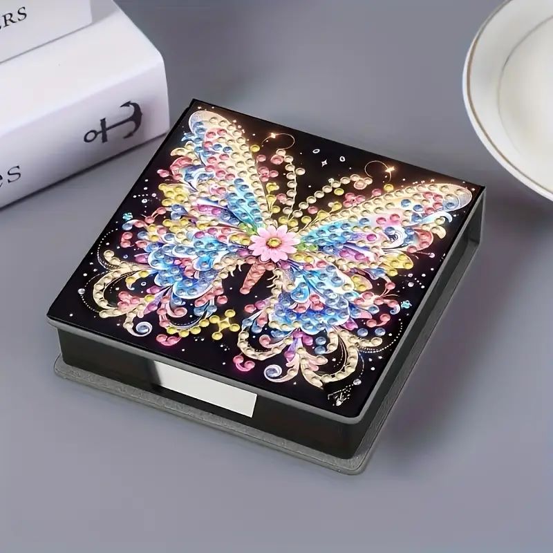 DIY diamond painting note paper holder kit. A black note box with a butterfly design on the lid, ready to be decorated with crystal rhinestones.