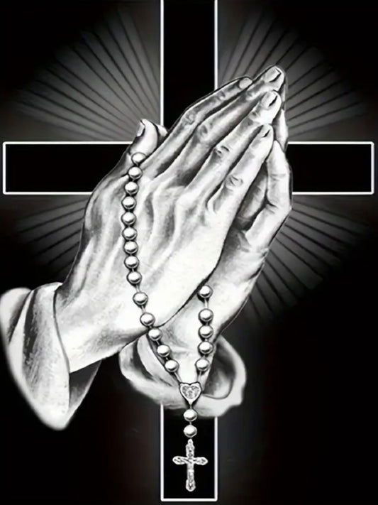 A diamond art kit depicting a pair of hands in a praying position holding a rosary with a cross in the background, symbolizing faith and devotion.