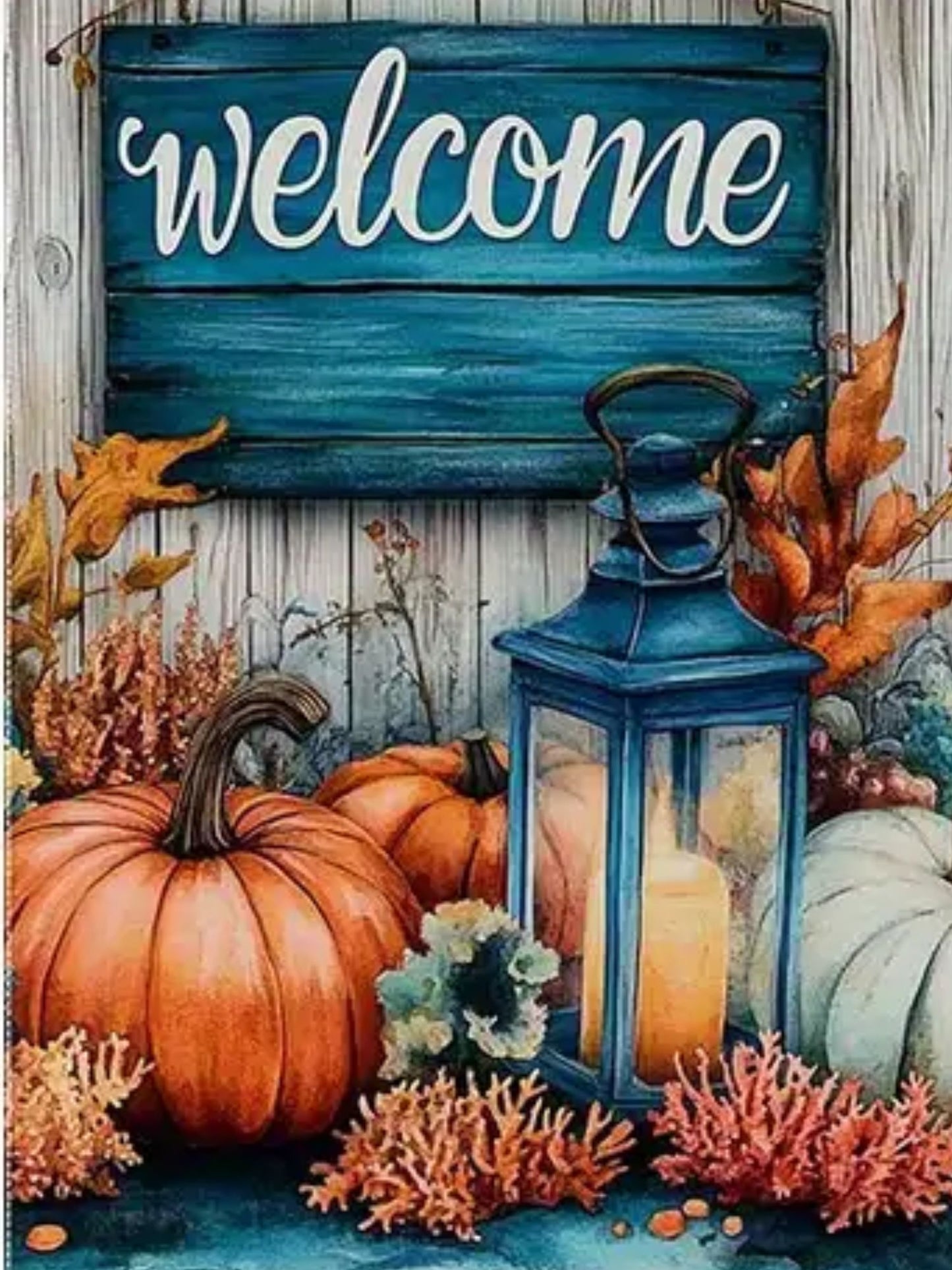 Decorative sign with 'welcome' text, pumpkins, lantern, and autumn leaves on a wooden background.