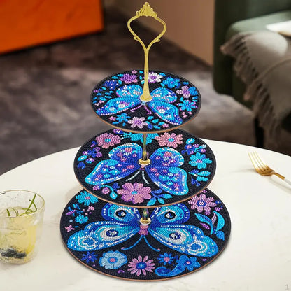 Three-tiered decorative stand with butterfly design on a table.