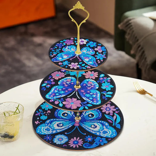 Three-tiered decorative stand with butterfly design on a table.