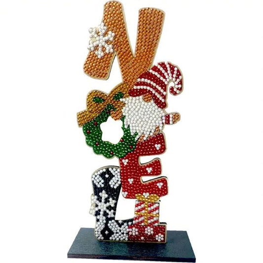A completed diamond painting tabletop sign that spells NOEL vertically on a dark base, with each letter decorated with Christmas motifs like a gnome, wreath, and snowflakes.
