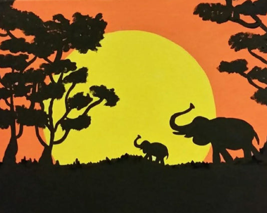 Silhouettes of elephants and trees against a sunset sky