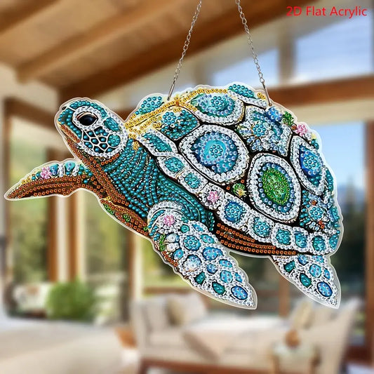 A completed diamond painting suncatcher shaped like a sea turtle, decorated with blue, teal, and white crystal rhinestones, hanging by a silver chain