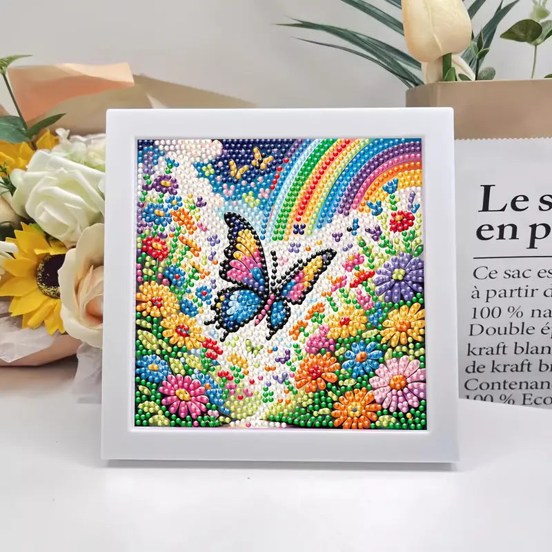 Framed artwork with a butterfly and rainbow design on a white surface with flowers and text in the background.