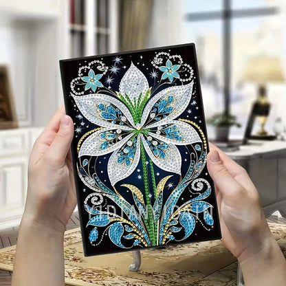 Decorative notebook with floral design held by hands in a blurred indoor setting