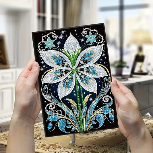 Decorative notebook with floral design held by hands in a blurred indoor setting