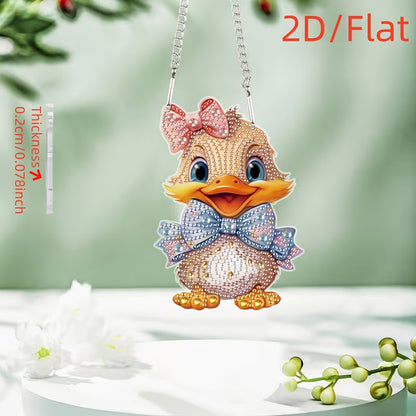 A 2D flat diamond painting pendant shaped like a cute duckling, decorated with pink, blue, and gold rhinestones, hanging from a silver chain against a soft green background with decorative white flowers.