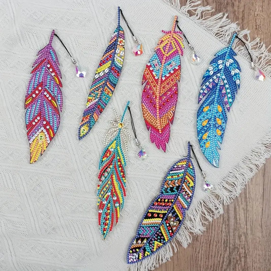 Colorful beaded diamond art feather bookmarks on a textured surface