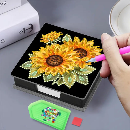 Person using a pink tool to work on a diamond painting project with a sunflower design.