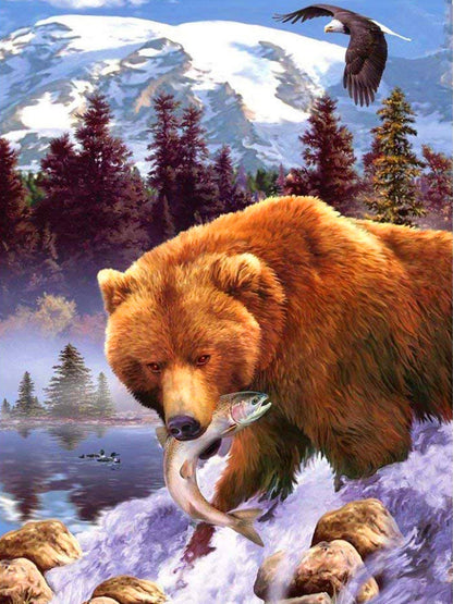 Brown Bear Fishing Diamond Painting Kit. A large brown bear with a fish in its mouth standing in a river with mountains and trees in the background.